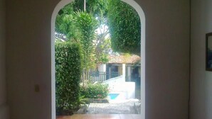 An arched doorway leading to a courtyard with a tiled floor, a small pool, and lush greenery. - Hotel Real de San Diego (Taxco)