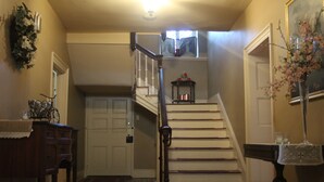 A staircase with a handrail, a door at the bottom, and a small table with a vase of flowers. - Stocks Manor Bed and Breakfast (Mechanicsburg)