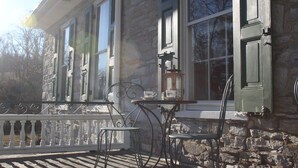 A stone building with a porch, a table, and two chairs. - Stocks Manor Bed and Breakfast (Mechanicsburg)