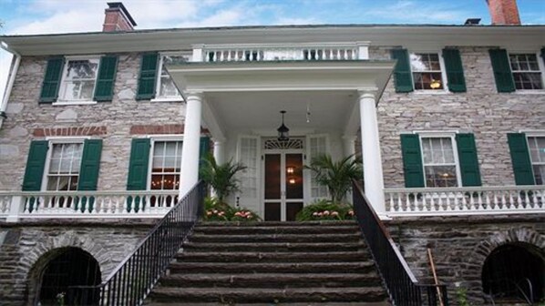 A stone building with a central entrance, green shutters, and a white porch. - Stocks Manor Bed and Breakfast (Mechanicsburg)
