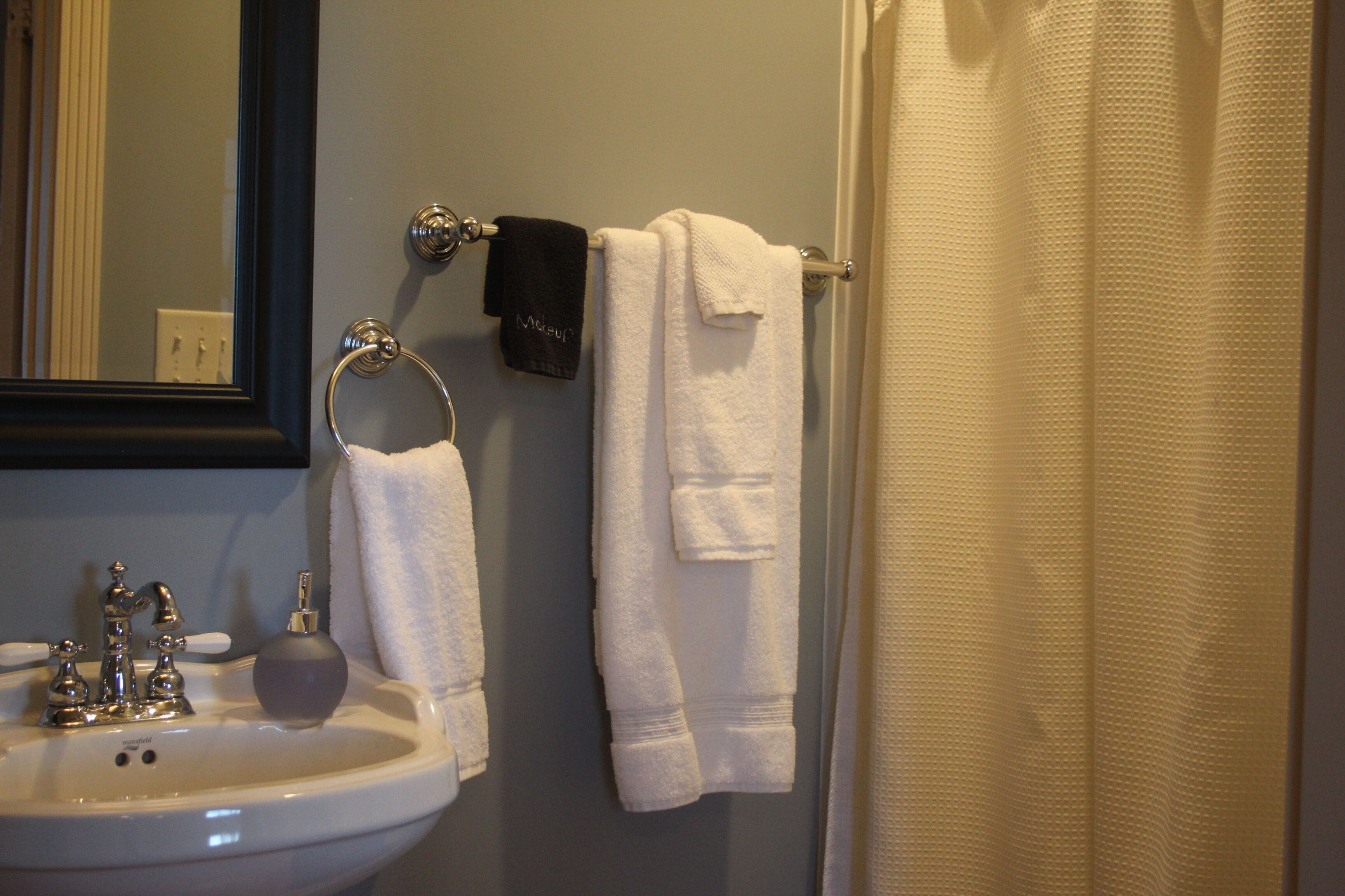 A bathroom with a sink, mirror, and towel rack.