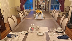 A formal dining room with a long table set for a meal, surrounded by chairs. - Stocks Manor Bed and Breakfast (Mechanicsburg)