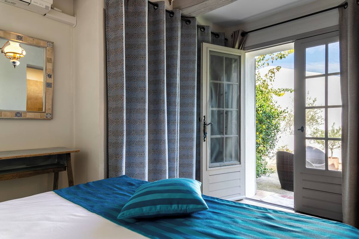 Ein Schlafzimmer mit einem Bett, einer Tür, die auf einen Balkon führt, und einem Spiegel an der Wand.