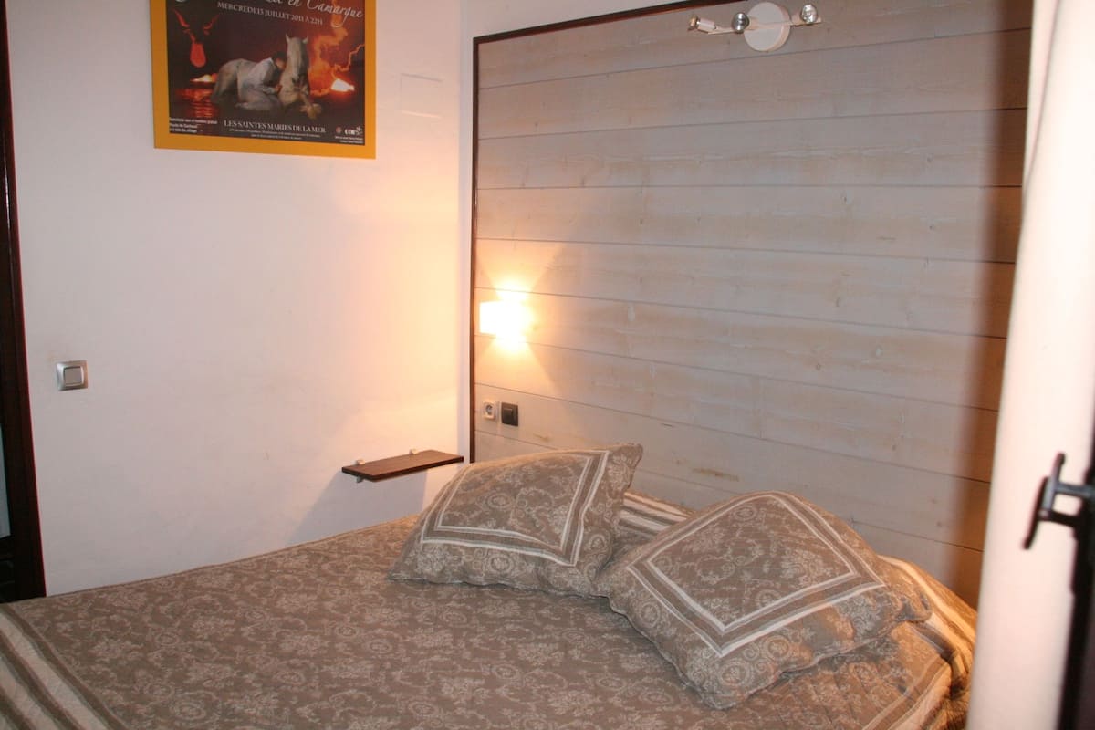Ein Schlafzimmer mit einem Holzkopfteil, zwei gemusterten Kissen, einem Nachttisch und einem Bild an der Wand.