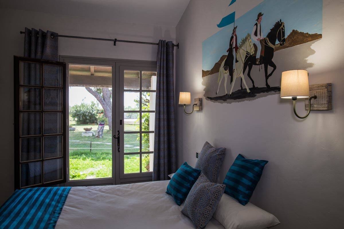 Ein Schlafzimmer mit einem großen Bett, Blick ins Freie und einem Gemälde von Reitern an der Wand.