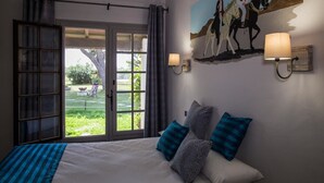 Un dormitorio con una cama grande, vistas al exterior y un cuadro de jinetes en la pared.