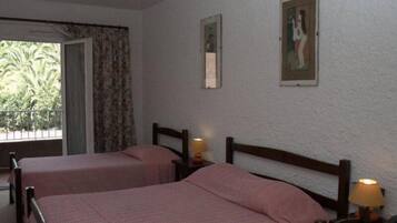 A room with two single beds, a window with curtains, and a door.