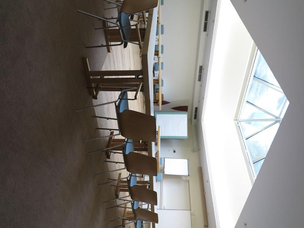 A conference room with a high ceiling, a whiteboard, and a large window.