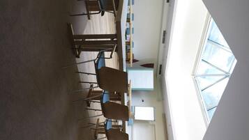 A conference room with a high ceiling, a whiteboard, and a large window.