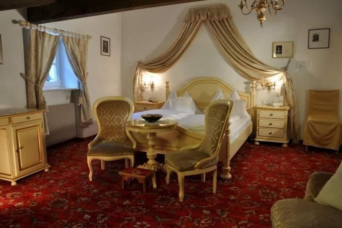 Une chambre à coucher comprenant un lit, deux chaises, une table, une table de chevet et une commode.