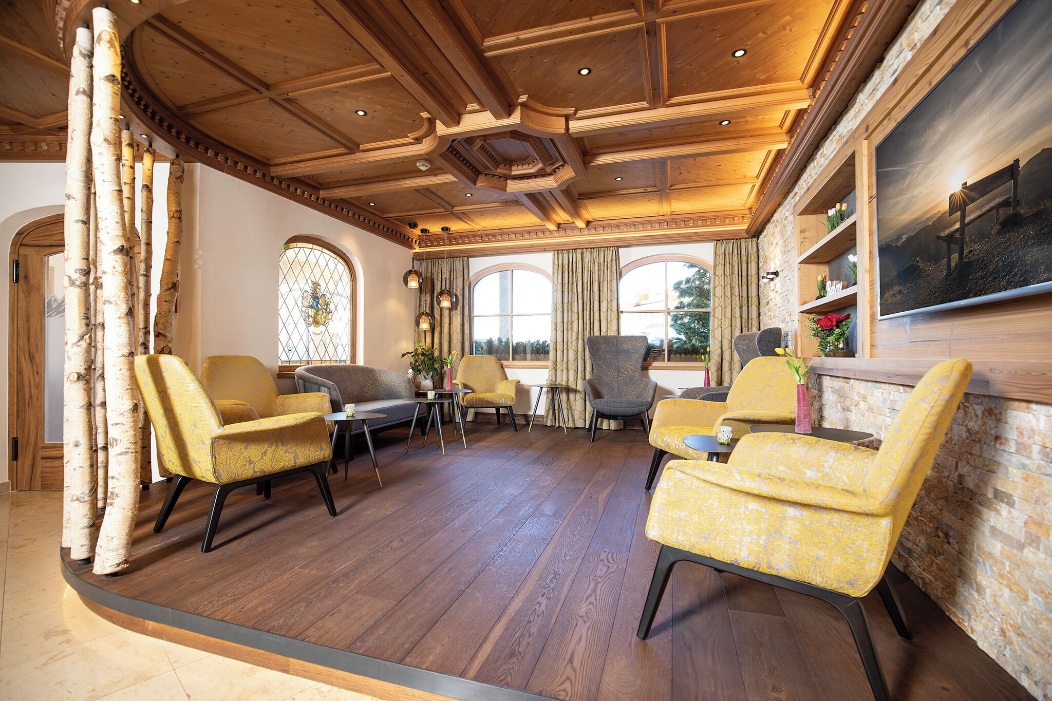 A spacious room with wooden flooring, multiple seating areas, and large windows.
