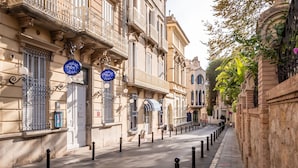 A street lined with historic buildings, featuring ornate balconies and classic architecture.