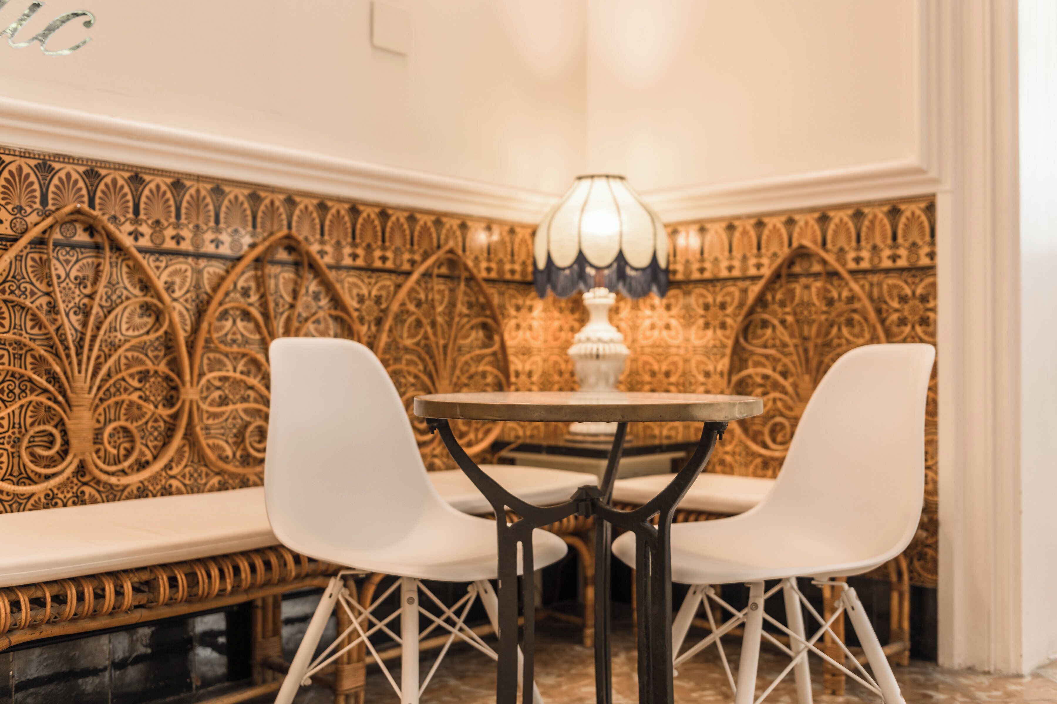 A corner seating area with ornate wall patterns, a round table, and two white chairs.