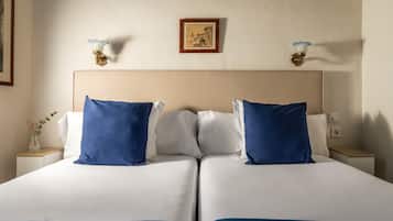 A double bed with white and blue bedding, two bedside tables with lamps, and a framed artwork on the wall.