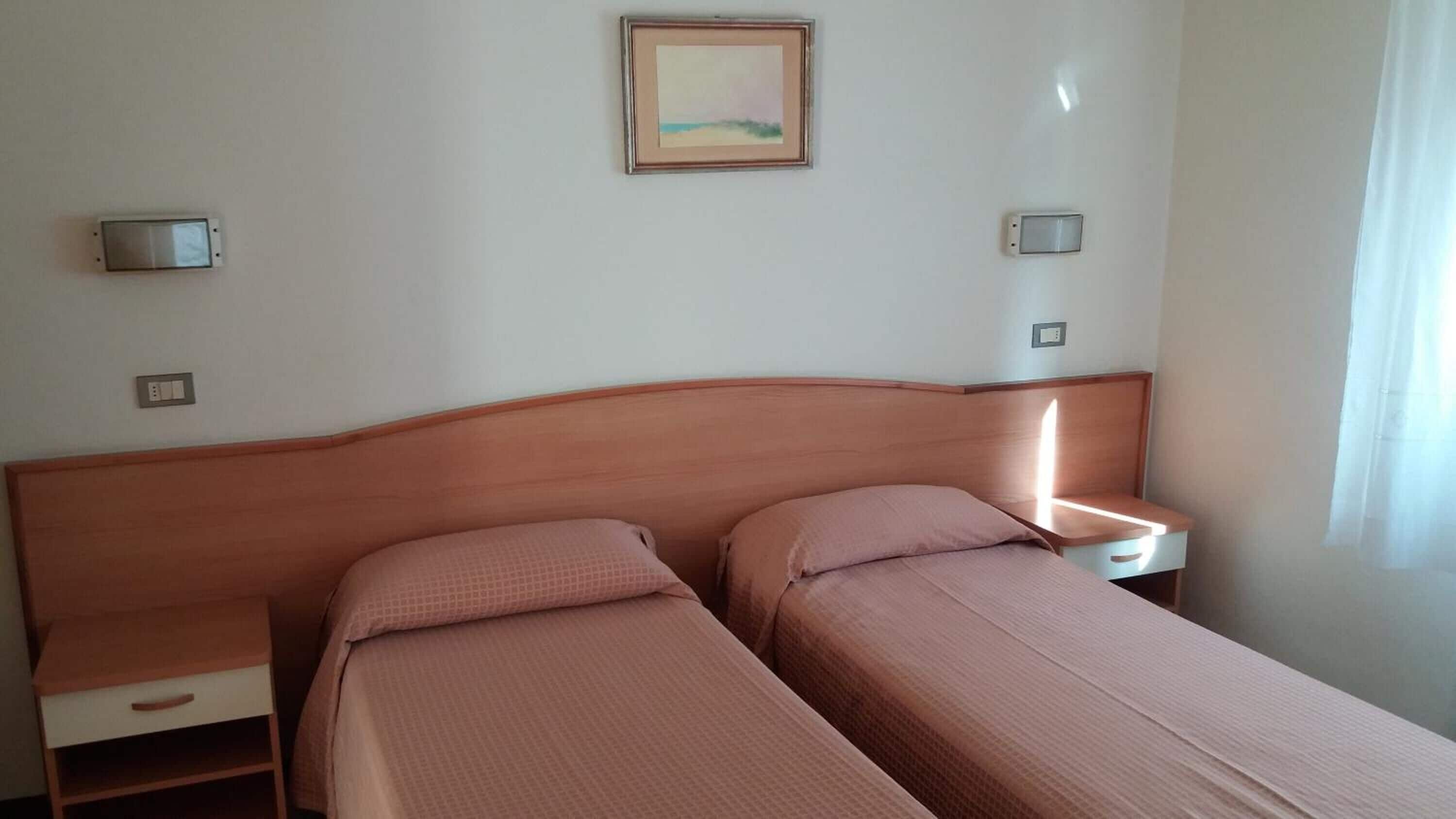 Ein Doppelbett mit Holzfußteil, zwei Nachttische und ein Bild an der Wand.