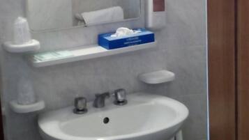 Ein Badezimmer mit einem weißen Waschbecken, einem Spiegel und einer Taschentuchbox auf der Ablagefläche.