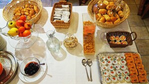 A buffet table with various food items including fruits, pastries, and packaged snacks.