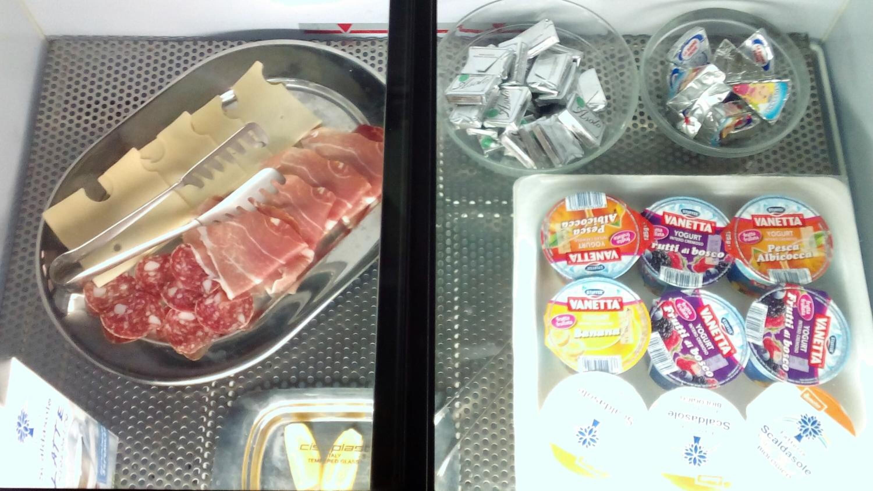 A refrigerator containing various food items including sliced meats, packaged cheese, and yogurt.