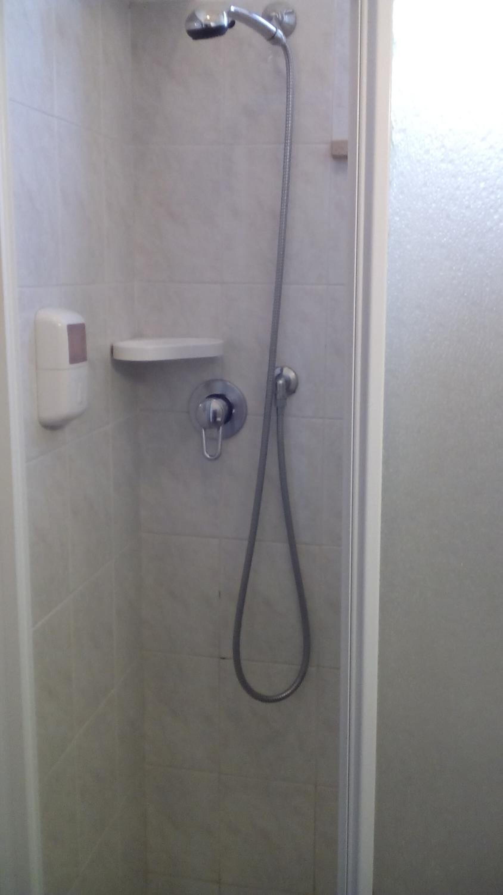 Eine Dusche mit Handbrause und Wandarmatur.