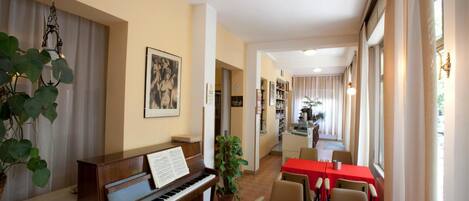 A dining area with a piano, red tables, and chairs.