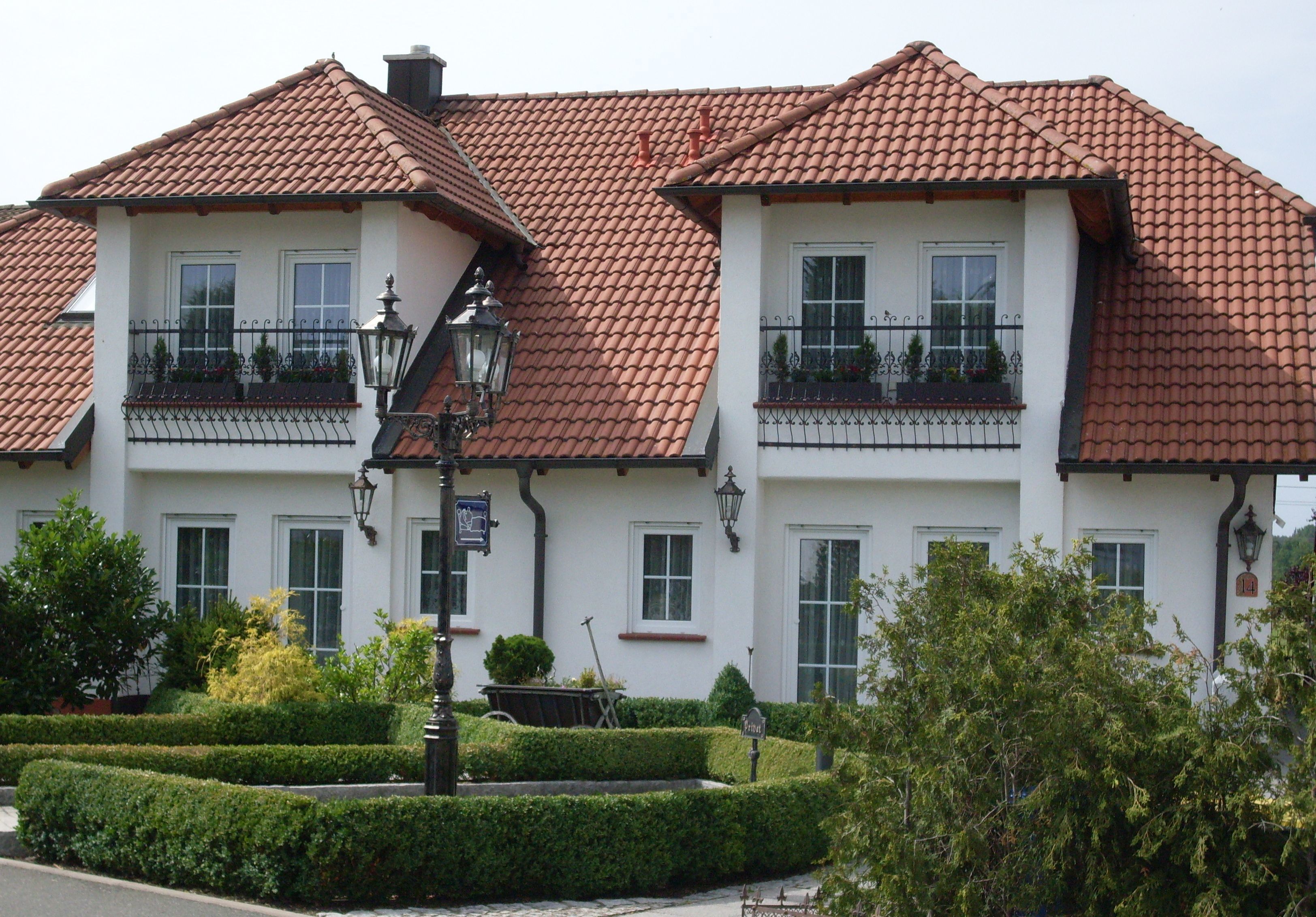 A two-story building with a red-tiled roof, white walls, and multiple windows.