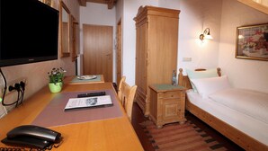 A room with a wooden desk, a bed, a nightstand, a television, and a painting on the wall. - Gäste- und Boardinghaus Klara Birnbaum (Erlangen)