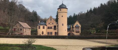 A castle with a central tower, a smaller building to the left, and a bridge connecting them.