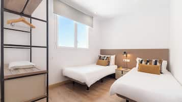 Una habitación de hotel con dos camas, un armario, una ventana y una mesita de noche con lámpara.