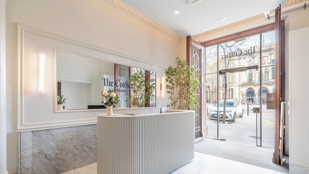 Ett entrérum med ett marmorgolv, en receptionsdisk, en stor spegel och utsikt över gatan utanför.