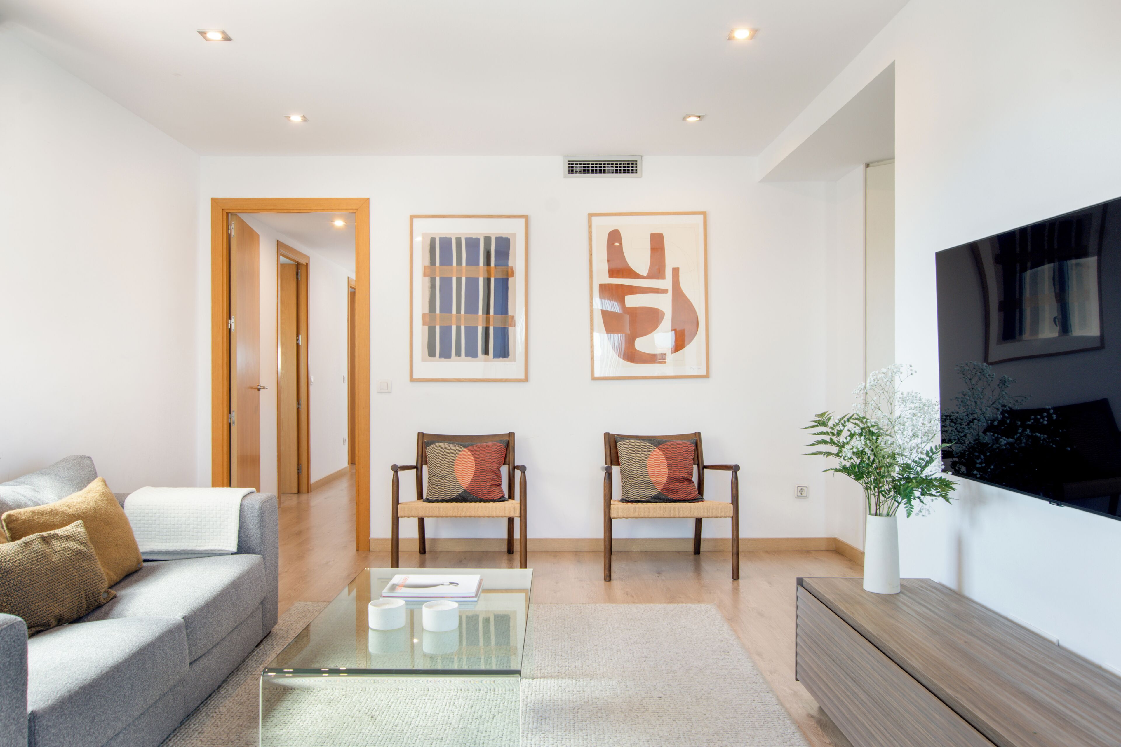 A modern living room with a sofa, two chairs, a coffee table, and artwork on the wall.
