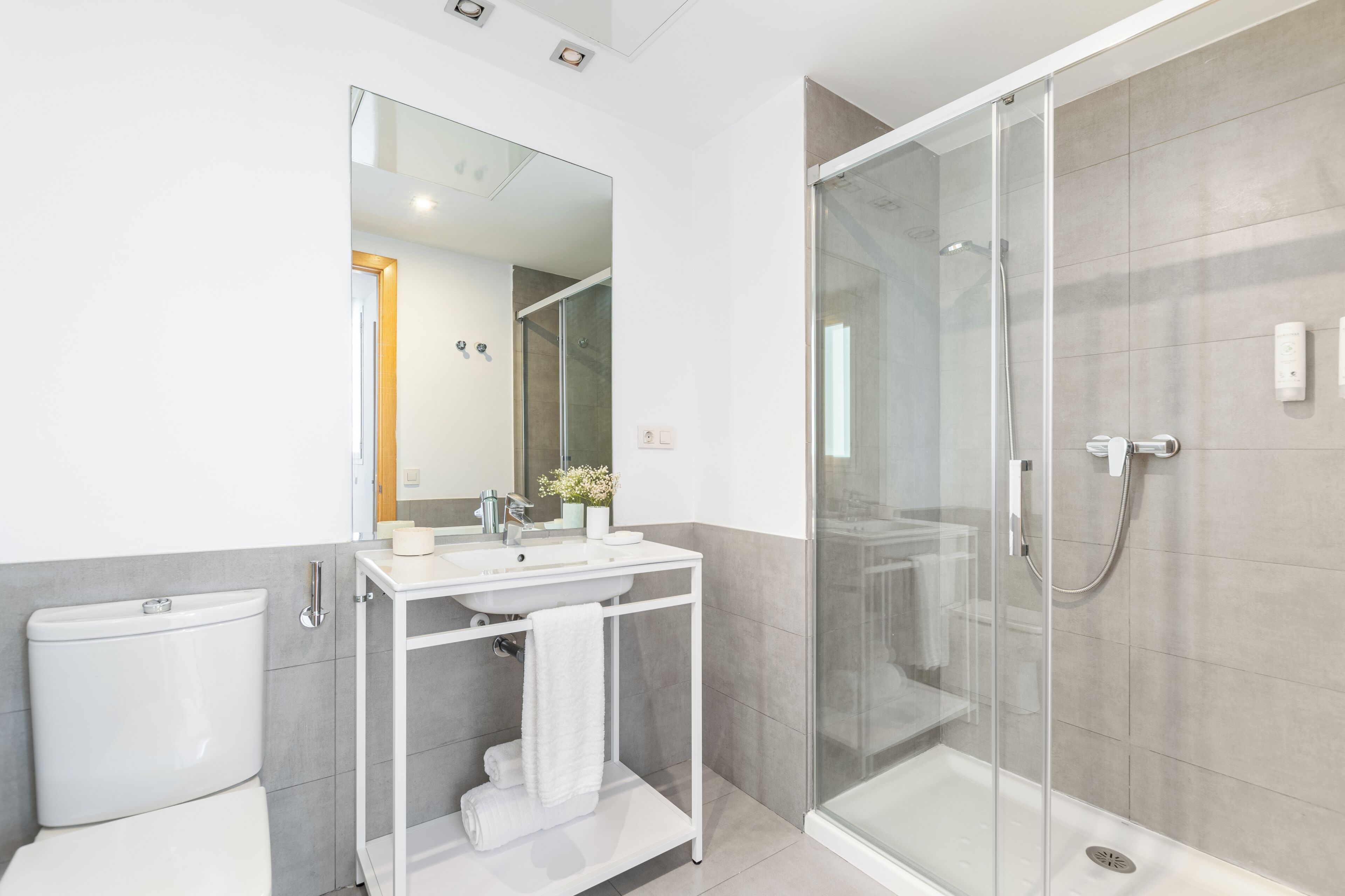 A modern bathroom with a glass-enclosed shower, a white sink, and a toilet.