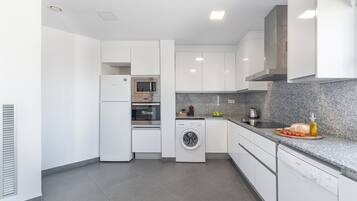 A modern kitchen with white cabinets, a built-in oven, microwave, and dishwasher.