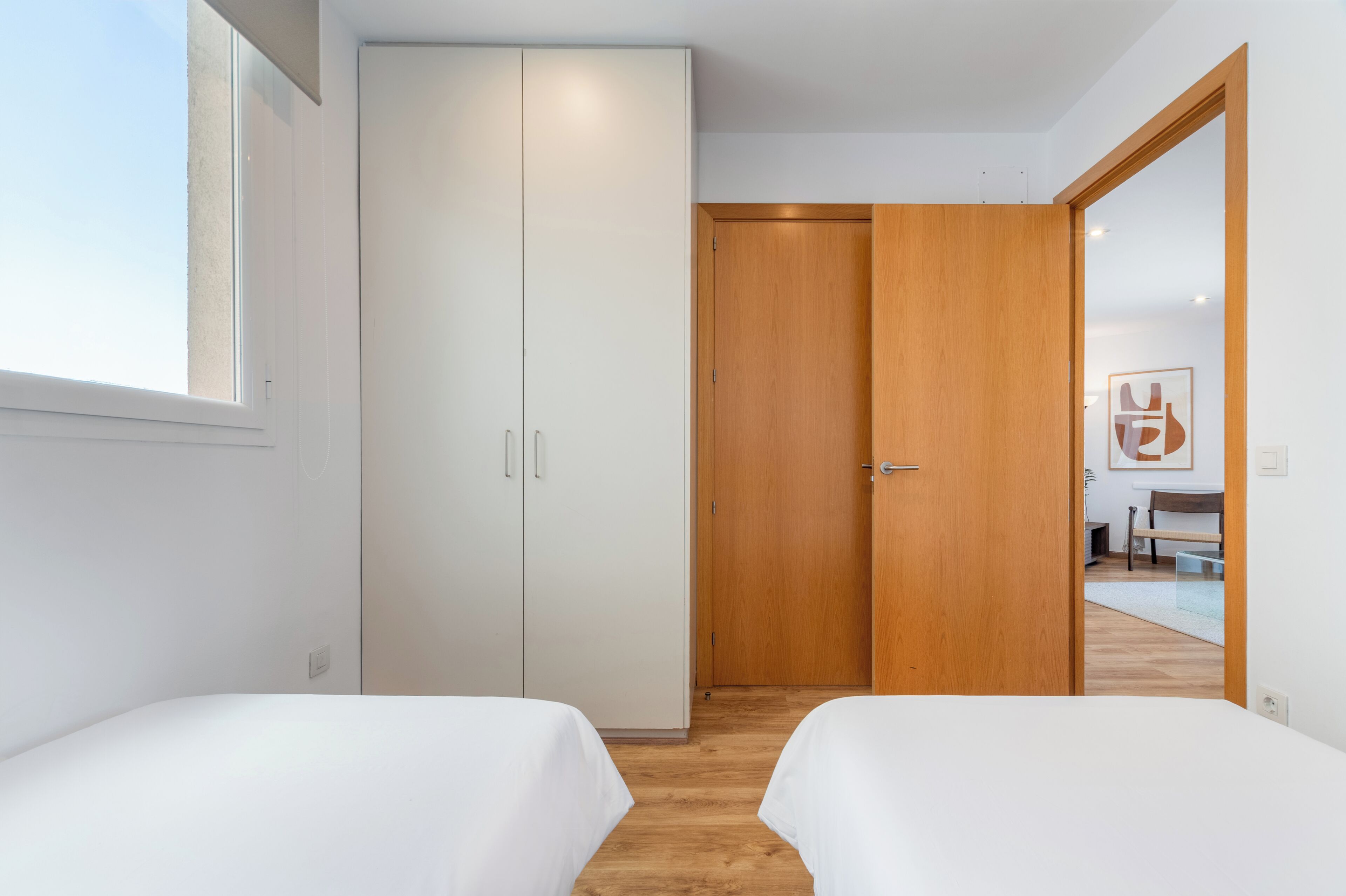 A bedroom with two beds, a wardrobe, and a wooden door.