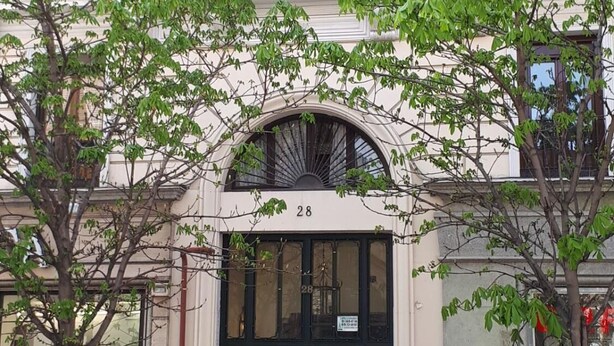 A building with a large arched entrance, numbered 28, and several parked motorcycles outside. - Hostal Pacios (Madrid)