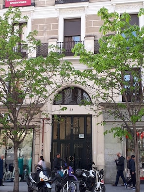 A building with a large arched entrance, numbered 28, and several parked motorcycles outside. - Hostal Pacios (Madrid)