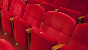 Rows of red theater seats with wooden armrests, each seat labeled with a number. - Hostal Pacios (Madrid)