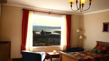 A room with a bed, a chair, a small table, and a window with curtains.