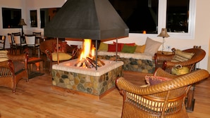 Una sala de estar acogedora con chimenea de piedra, muebles de mimbre y una pared de acento de piedra.