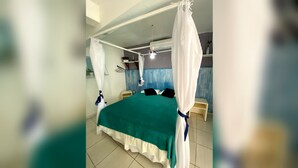 A room with a bed, a bedside table, a hanging light fixture, and a curtain. - Kuara Hostel Natal (Parnamirim)