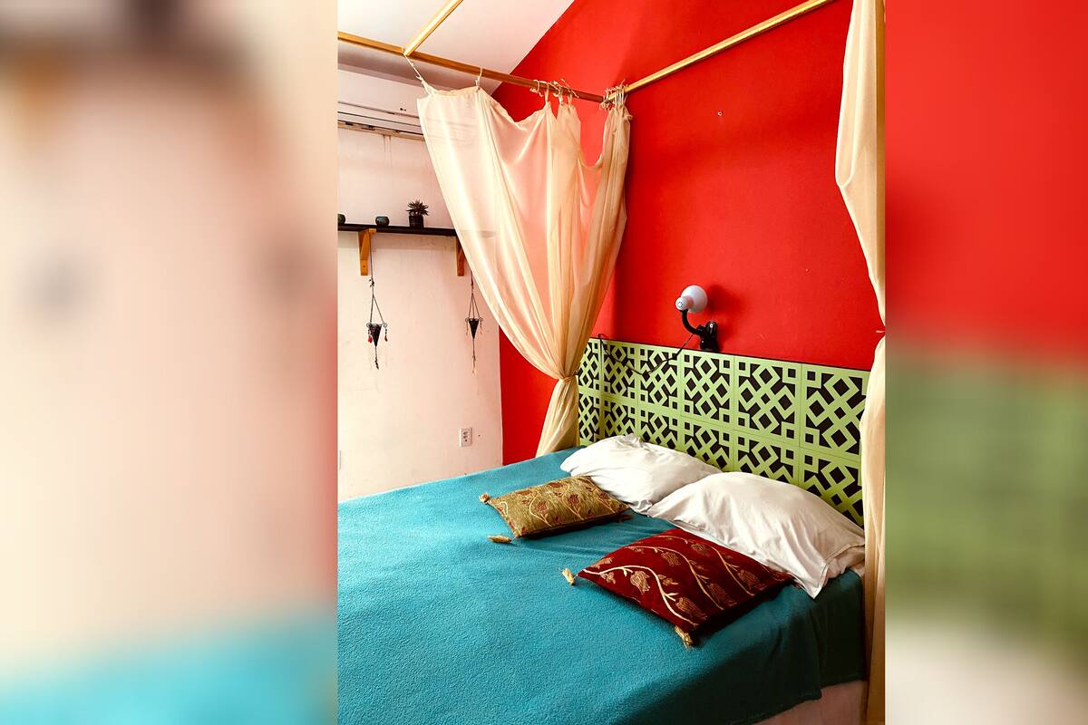 A bed with a green headboard, a blue bedspread, and two pillows.