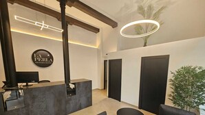 Zona de recepción con diseño moderno, que incluye un mostrador de recepción, área de estar y una planta grande en maceta.