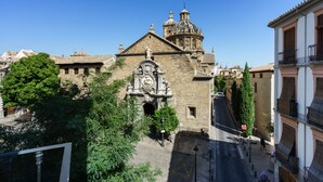 Un edificio histórico con una cúpula destacada y una fachada elaborada, rodeado de árboles y otros edificios.