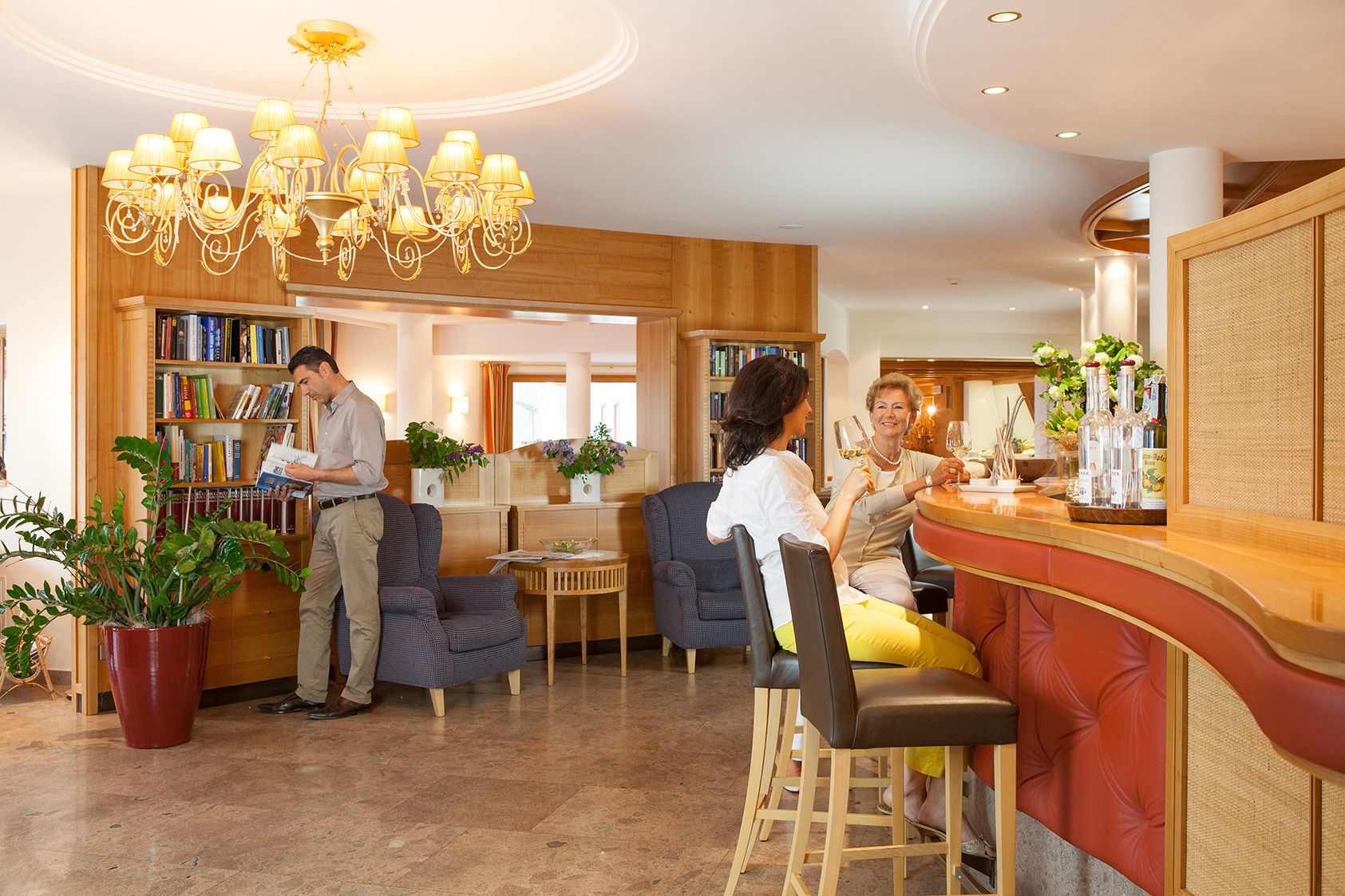 Un vestíbulo de hotel con mostrador de recepción, zona de estar y una estantería llena de libros.