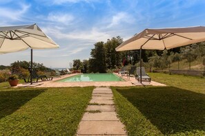 A backyard with a swimming pool, two umbrellas, and lounge chairs. - Agriturismo La Gismonda (Bracciano)
