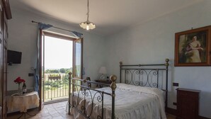 Une chambre à coucher avec un lit, une table ornée de fleurs, une lampe et un tableau accroché au mur.