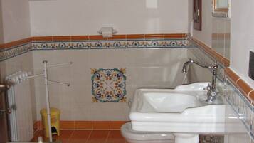 Un baño con dos lavamanos, un inodoro, una ducha y un espejo.