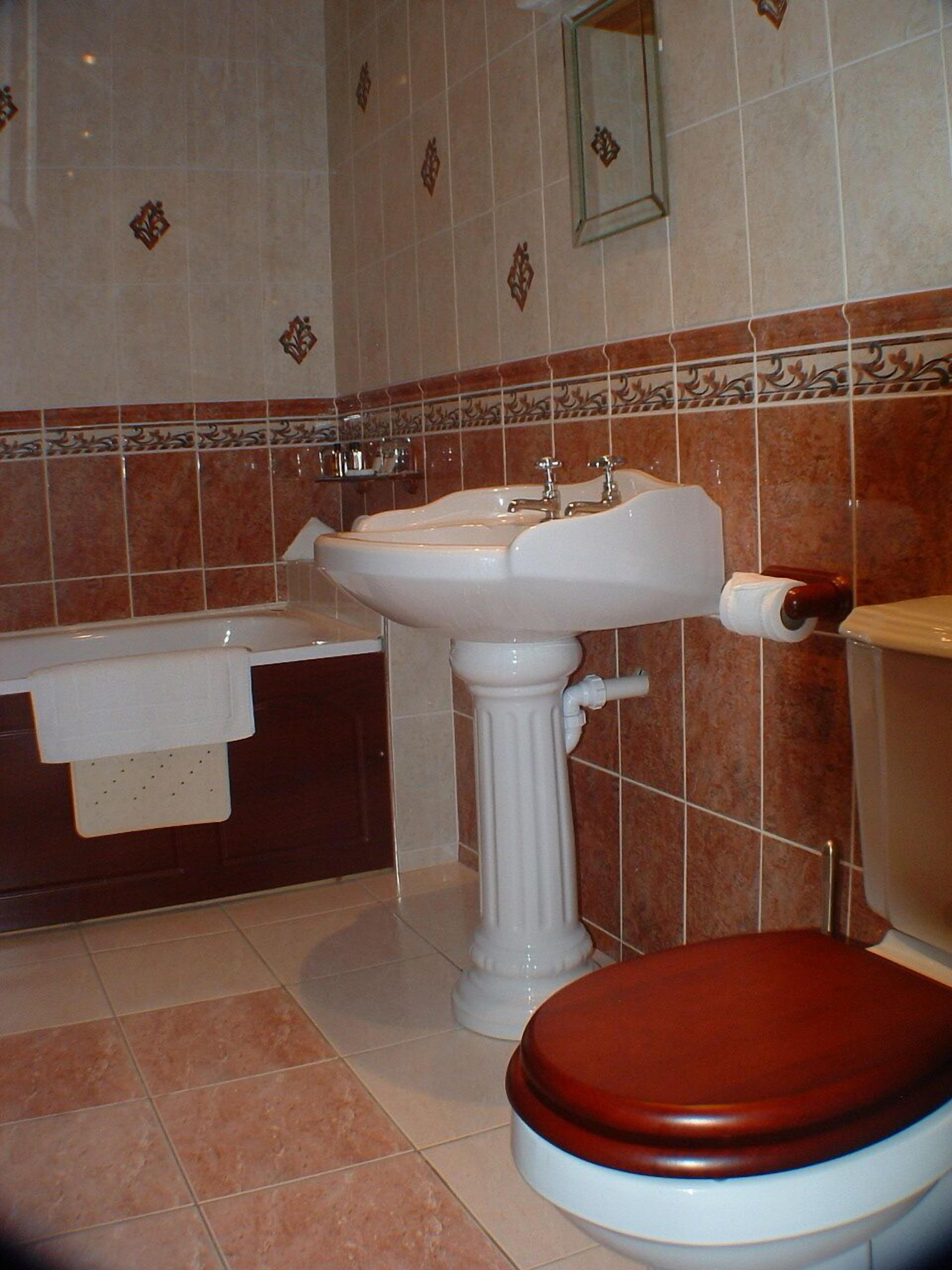 A bathroom with a pedestal sink, a bathtub, and a toilet.