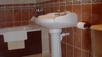 A bathroom with a pedestal sink, a bathtub, and a toilet.