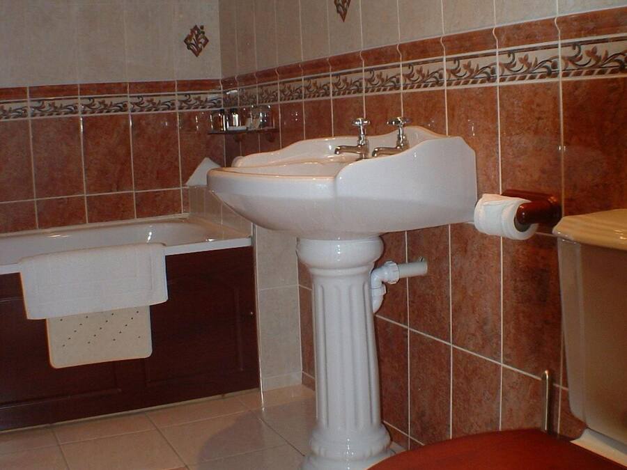 A bathroom with a pedestal sink, a bathtub, and a toilet.