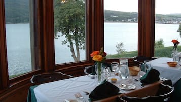 A dining table set for two with a view of a lake and hills.
